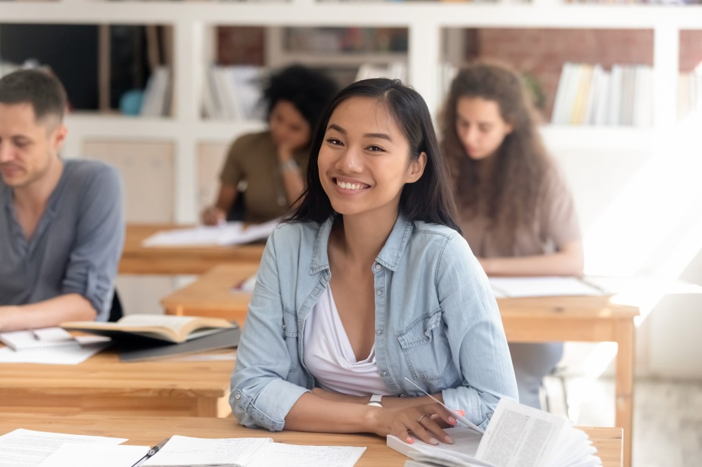 A high school student smiling sitting at her desk